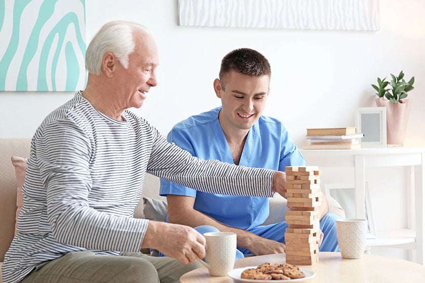 Senior-man-playing-board-game-with-his-caregiver-at-home-